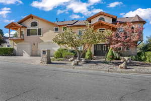 European style house featuring stone siding, stucco siding, a 4 car garage, driveway, and a balcony