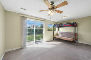 South bedroom with light colored carpet, ceiling fan, and sliding glass door