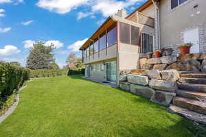 View of yard featuring a sunroom and a balcony