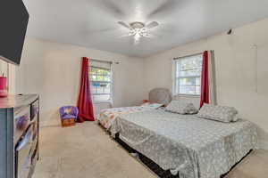 Bedroom with multiple windows, light carpet, and ceiling fan