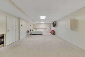 Carpeted bedroom with a paneled ceiling and wood walls