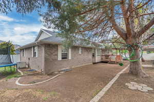 View of property exterior featuring a trampoline, a deck, brick siding, a shingled roof, and crawl space