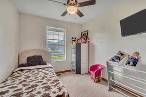 Bedroom with light colored carpet and a ceiling fan