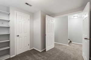 Unfurnished bedroom with dark carpet and a textured ceiling