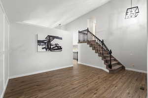 Unfurnished living room with dark wood finished floors, stairway, and high vaulted ceiling
