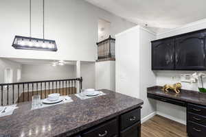 Kitchen with dark cabinets, dark wood-style floors, pendant lighting, and dark stone countertops
