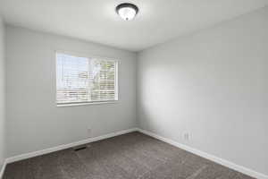 Unfurnished room with dark carpet and a textured ceiling