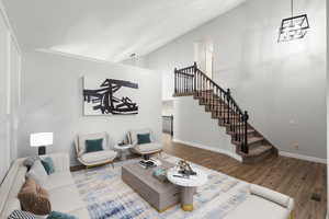 Living room with wood finished floors, stairs, and high vaulted ceiling