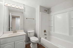 Bathroom with a textured ceiling, vanity, bathtub / shower combination, and dark wood-type flooring