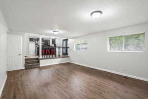 Unfurnished room with dark wood finished floors and a textured ceiling
