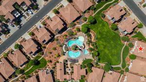 Aerial view of property and surrounding area featuring a pool area and nearby suburban area