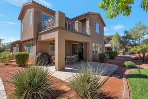 Back of property with a balcony, stucco siding, a patio area, and a tiled roof