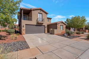 Mediterranean / spanish-style house with stone siding, a balcony, stucco siding, and driveway