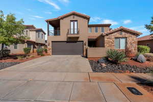 Mediterranean / spanish house featuring stone siding, a balcony, stucco siding, concrete driveway, and a garage
