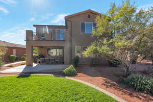 Rear view of house featuring stucco siding, a balcony, a patio, and a tiled roof