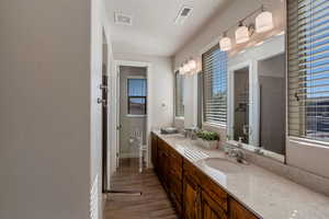 Full bathroom featuring double vanity, a shower stall, and wood finish floors
