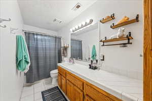 Bathroom featuring vanity, light tile patterned flooring, and a textured ceiling