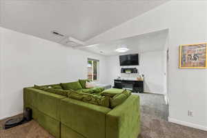 Carpeted living room with a textured ceiling and lofted ceiling