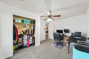 Carpeted office with a textured ceiling and ceiling fan