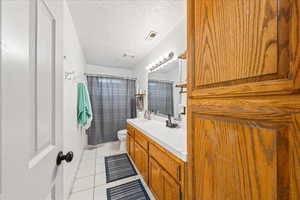 Full bathroom with vanity, light tile patterned floors, and a textured ceiling