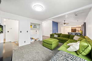Living area with a textured ceiling, light colored carpet, and a ceiling fan
