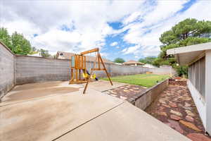 Fenced backyard with a playground and a patio