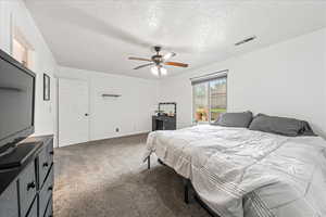 Bedroom with carpet floors, a ceiling fan, and a textured ceiling