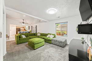 Carpeted living room featuring a textured ceiling and a ceiling fan