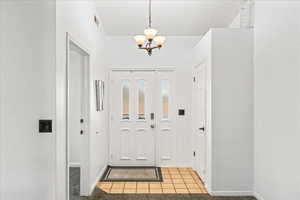 Foyer entrance featuring a chandelier and light tile patterned flooring