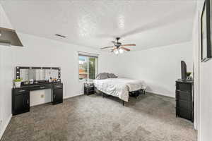 Carpeted bedroom featuring a textured ceiling and ceiling fan