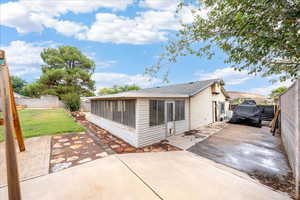 Rear view of house featuring a fenced backyard, a sunroom, and a patio