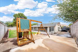 View of playground with a fenced backyard and a patio