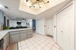 Kitchen featuring light countertops, a peninsula, open floor plan, light tile patterned floors, and dishwasher