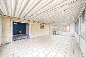 Unfurnished sunroom featuring ceiling fan and tile patterned floors