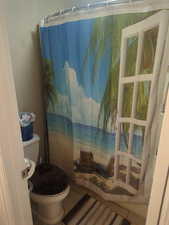 Bathroom featuring a shower with curtain, view of water and beach, and tile patterned floors