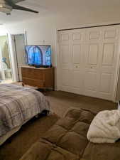 Carpeted bedroom featuring a closet, a textured ceiling, and a ceiling fan
