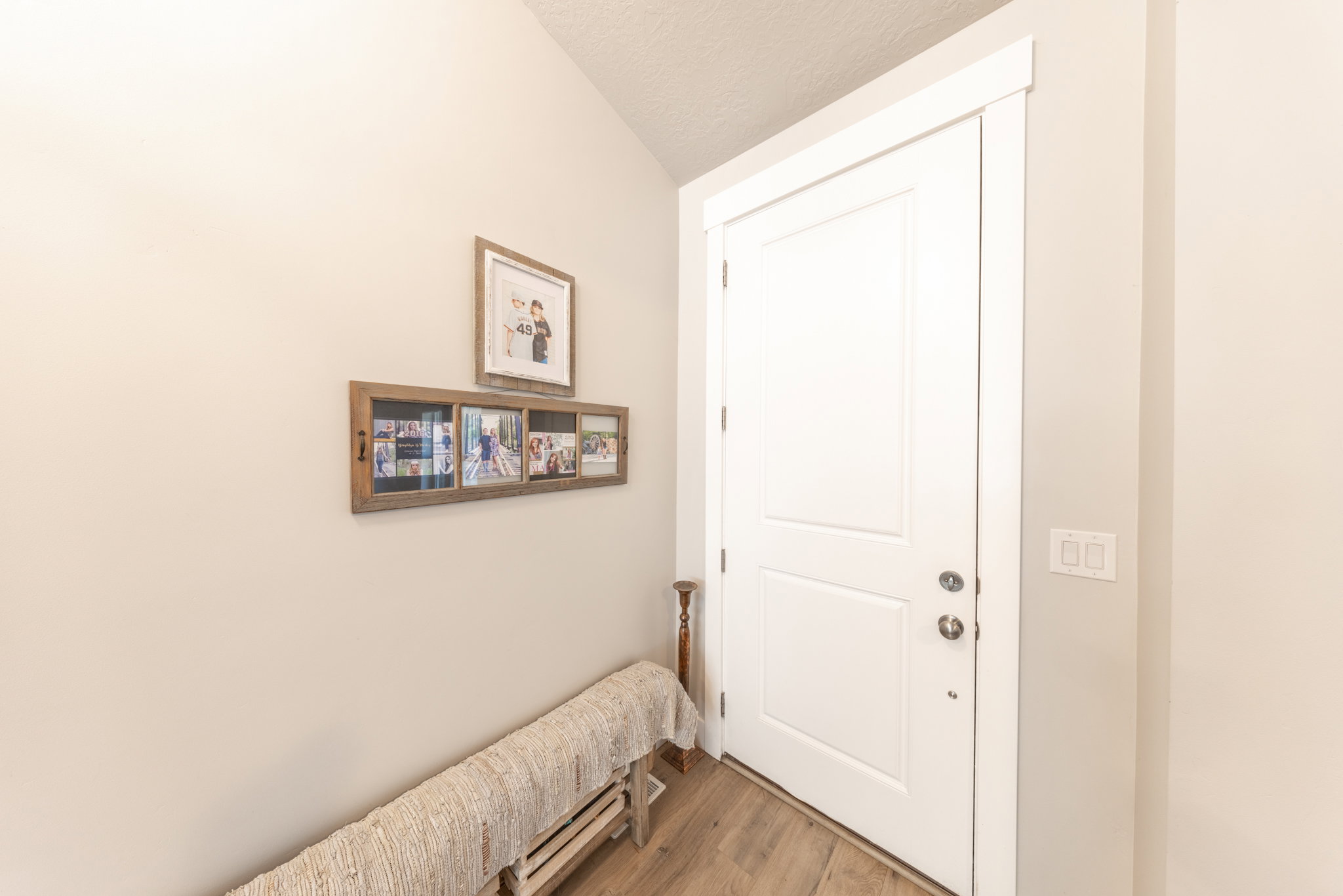 Doorway to outside featuring wood finished floors, a textured ceiling, and vaulted ceiling