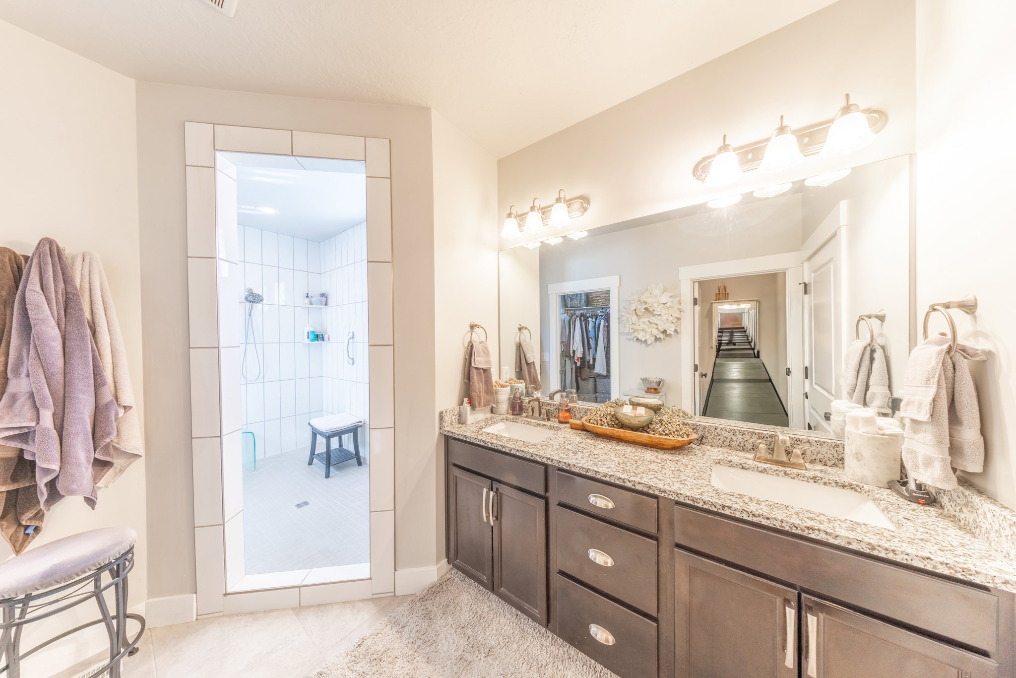 Full bath with double vanity, tiled shower, and light tile patterned floors
