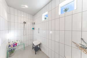 Bathroom featuring walk in shower, tile walls, and tile patterned floors