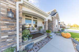 Doorway to property with stone siding and covered porch