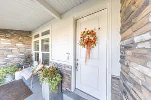 Doorway to property with stone siding and a porch