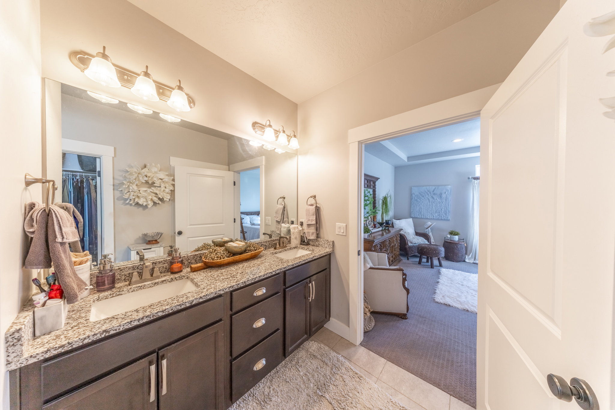 Ensuite bathroom featuring double vanity, light tile patterned flooring, and light colored carpet