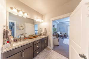 Ensuite bathroom featuring double vanity, light tile patterned flooring, and light colored carpet