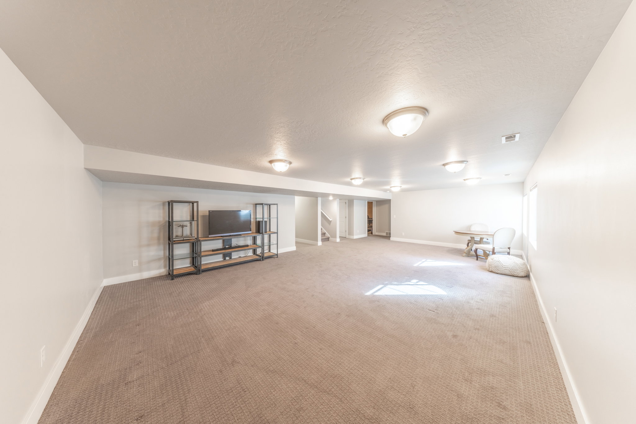 Finished basement featuring carpet flooring, a textured ceiling, and stairs
