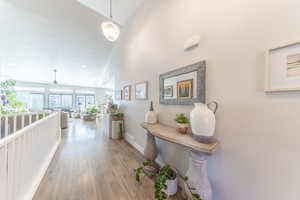 Hallway featuring high vaulted ceiling and wood finished floors