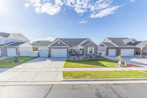 Craftsman-style house featuring driveway, stone siding, and an attached garage