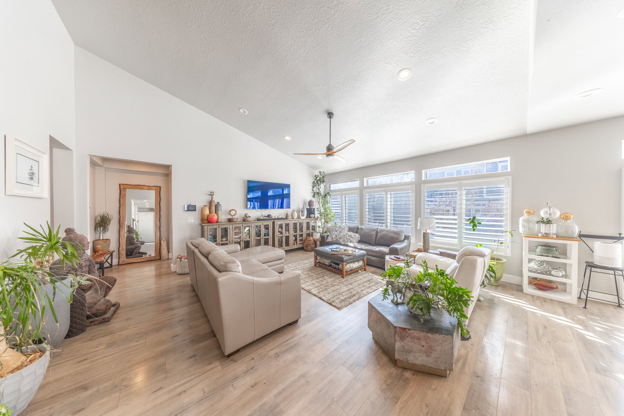 Living room with high vaulted ceiling, light wood-type flooring, a textured ceiling, ceiling fan, and recessed lighting