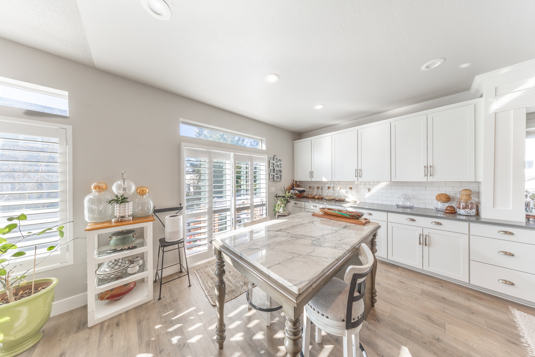 Kitchen with white cabinets, light wood-type flooring, backsplash, and recessed lighting