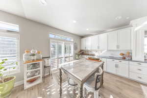 Kitchen with white cabinets, light wood-type flooring, backsplash, and recessed lighting