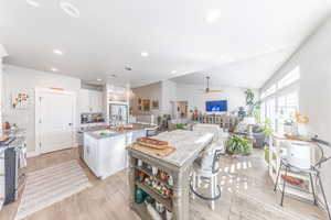 Kitchen featuring white cabinets, an island with sink, decorative light fixtures, light wood-style flooring, and recessed lighting